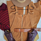 Brown leather vest, hat, and shoes on a textured surface