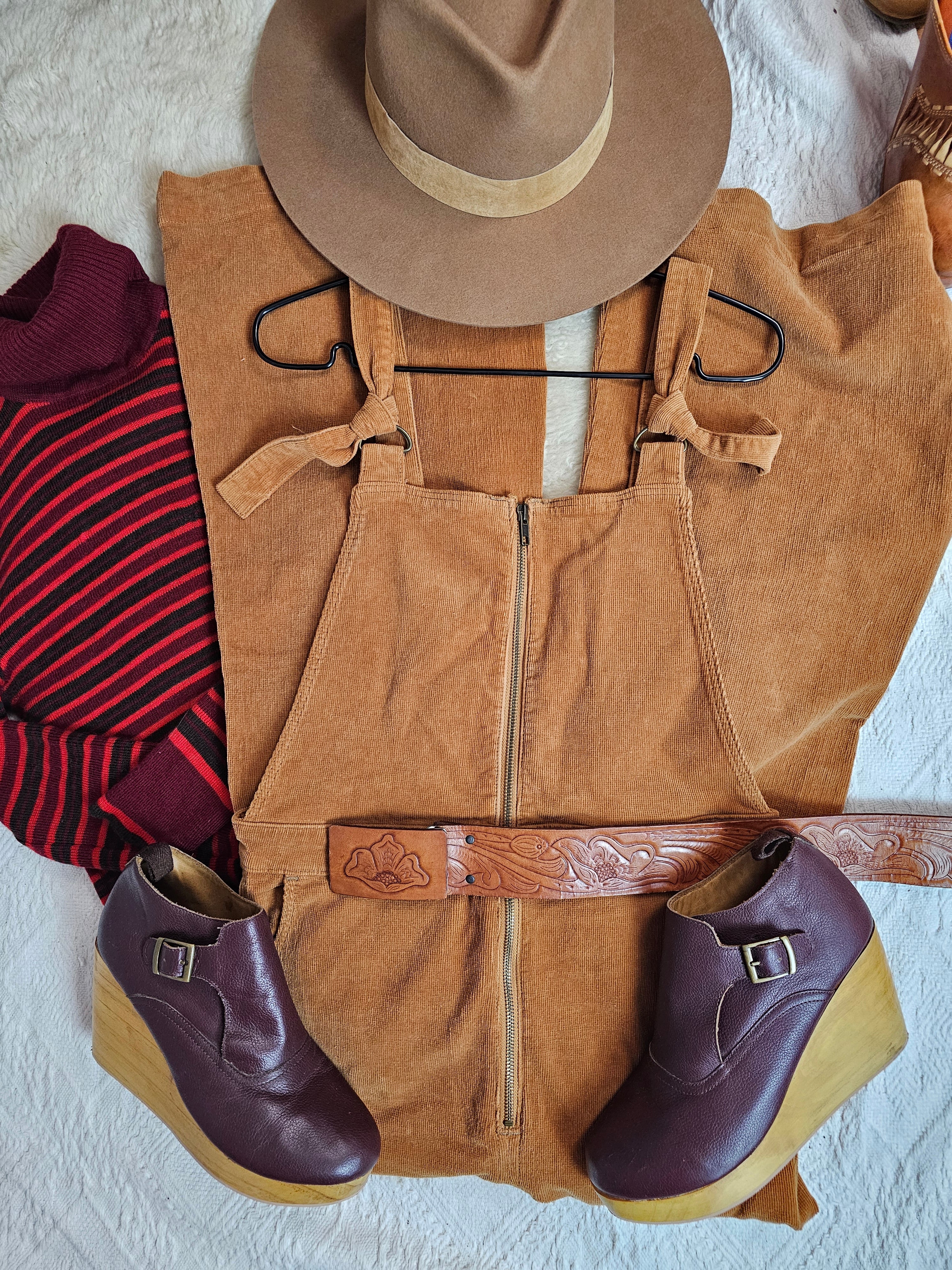 Brown leather vest, hat, and shoes on a textured surface