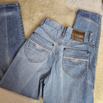 Pair of blue jeans laid flat on a textured beige surface