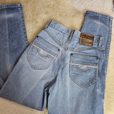 Pair of blue jeans laid flat on a textured beige surface