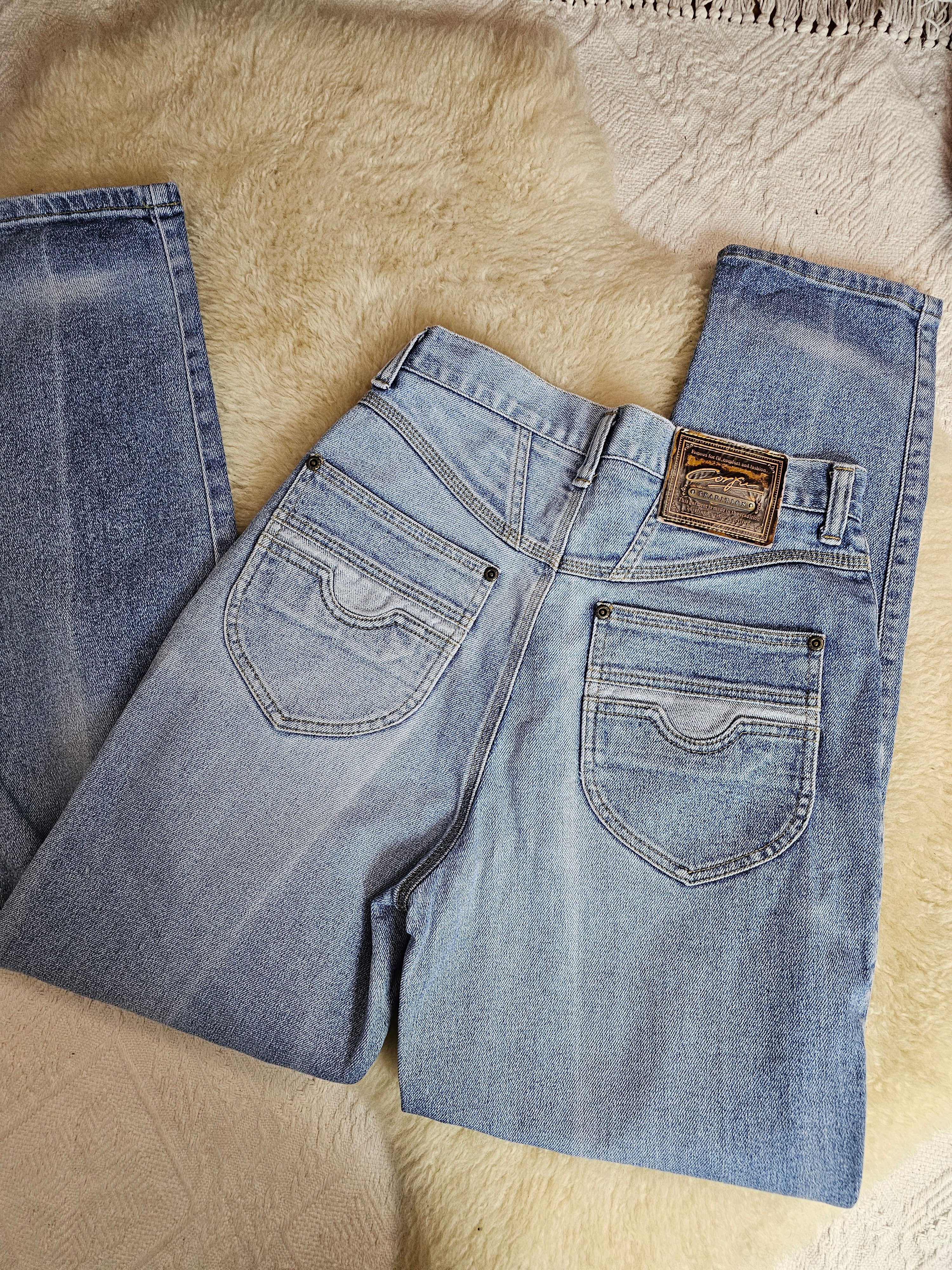 Pair of blue jeans laid flat on a textured beige surface
