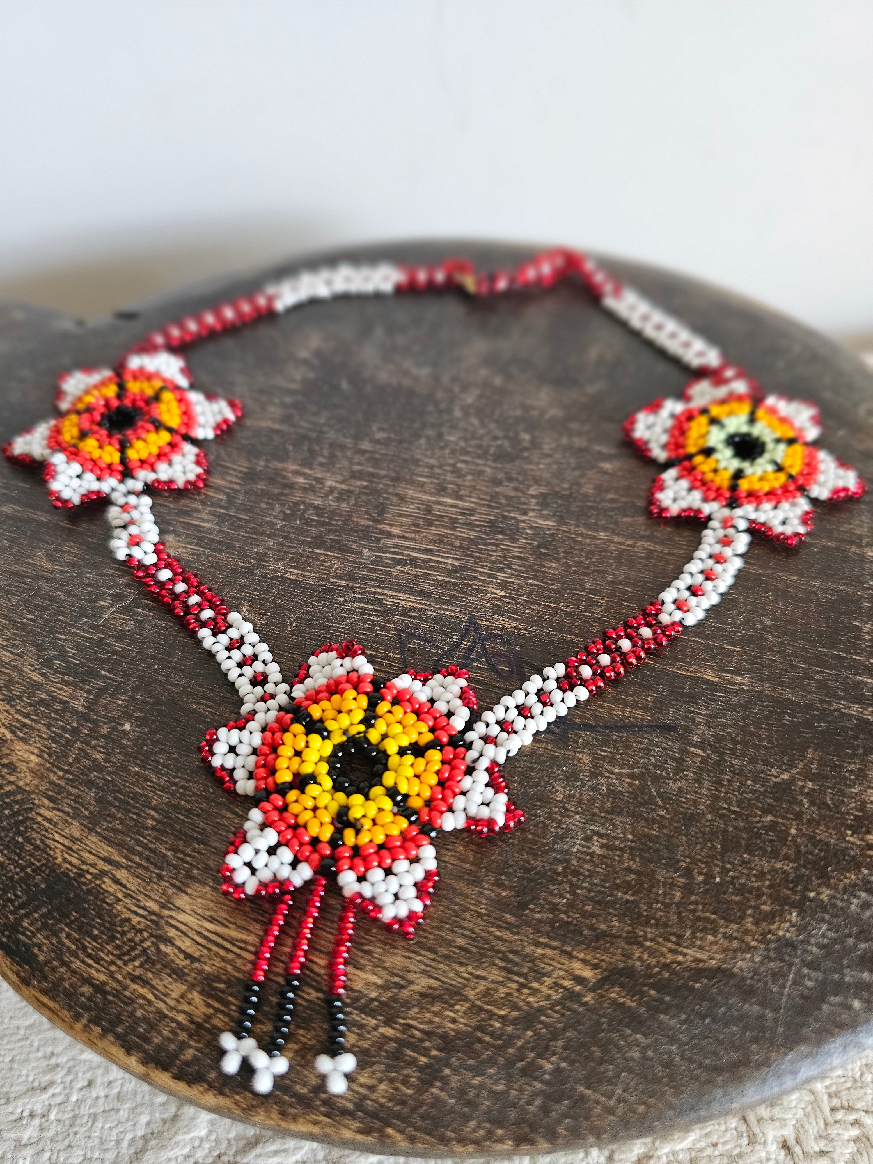 Beaded necklace with floral designs on a wooden surface