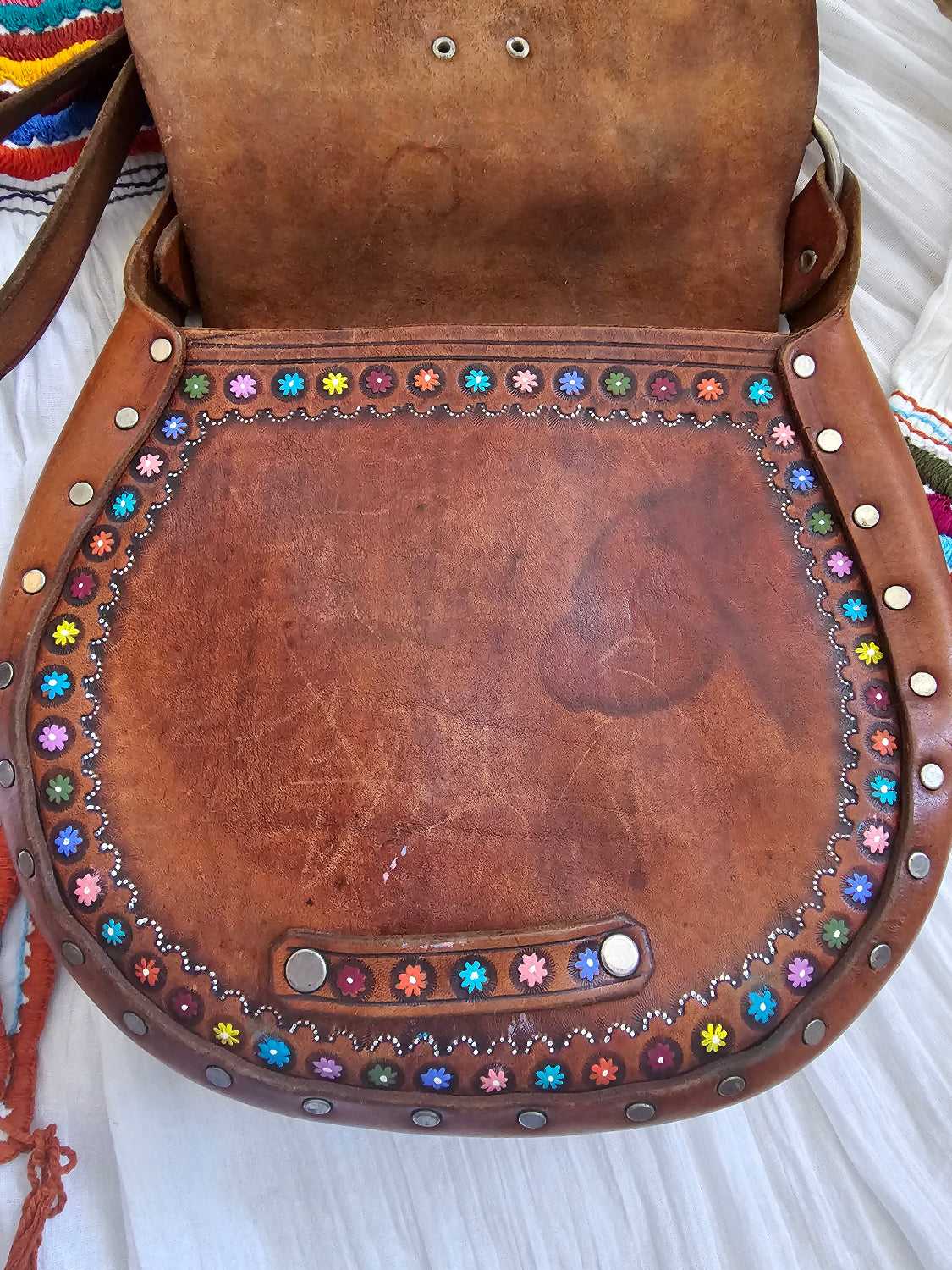 Brown leather saddle with colorful beadwork on a white background