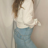 Person wearing a white shirt, blue jeans, and a brown hat lying on a beige surface.