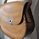 Brown leather saddle with intricate patterns on a vehicle ceiling