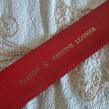 Red leather strap with embossed text on a textured white background