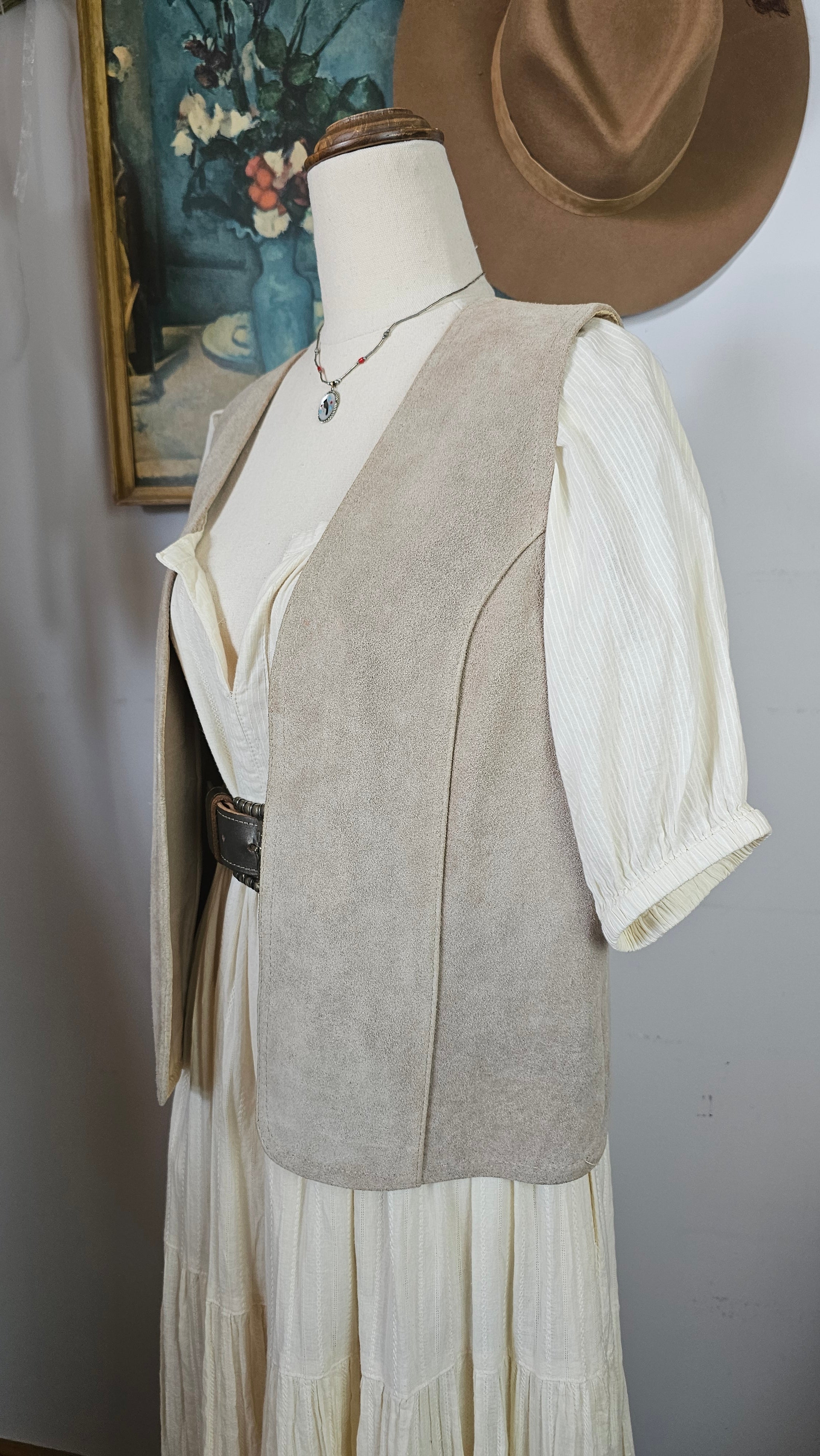 Mannequin wearing a beige suit with a white shirt and brown hat on a plain background