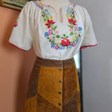 Embroidered white glove with floral patterns on a neutral background