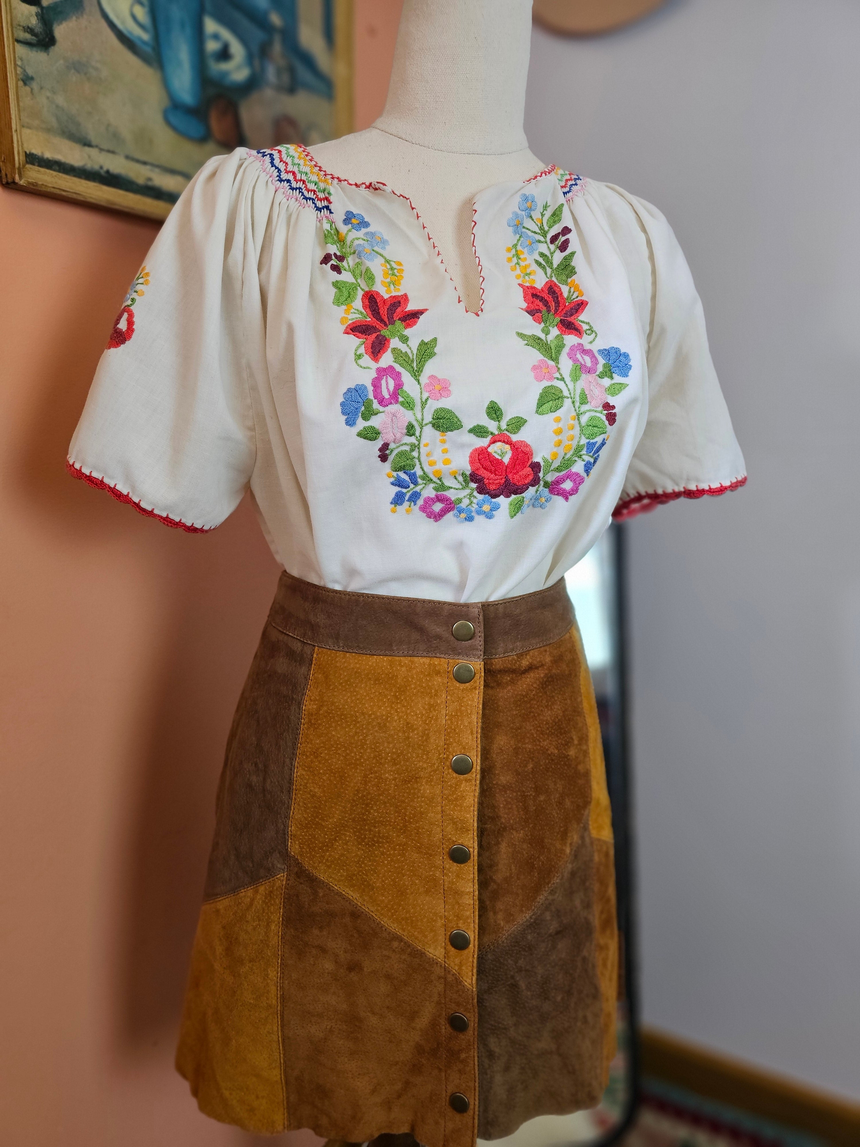 Embroidered white glove with floral patterns on a neutral background