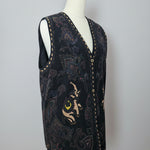 Embroidered black shoe with a cat design on a beige surface