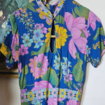 Floral fabric with pink, green, and yellow flowers on a blue background.