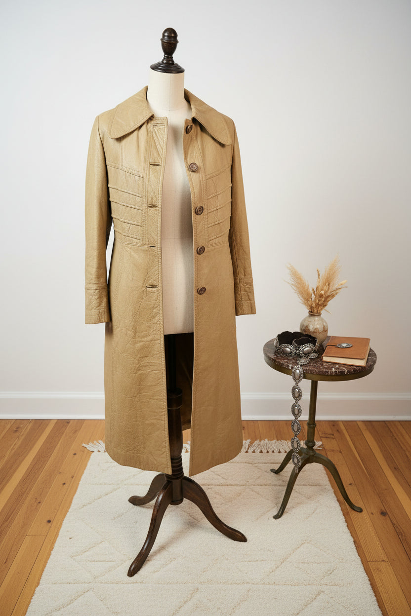 Beige trench coat on a textured white surface with wooden floor in the corner