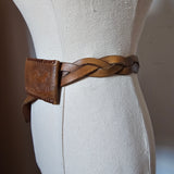 Close-up of a braided leather strap on a beige fabric background
