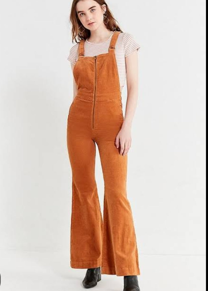 Person wearing brown corduroy overalls on a white background