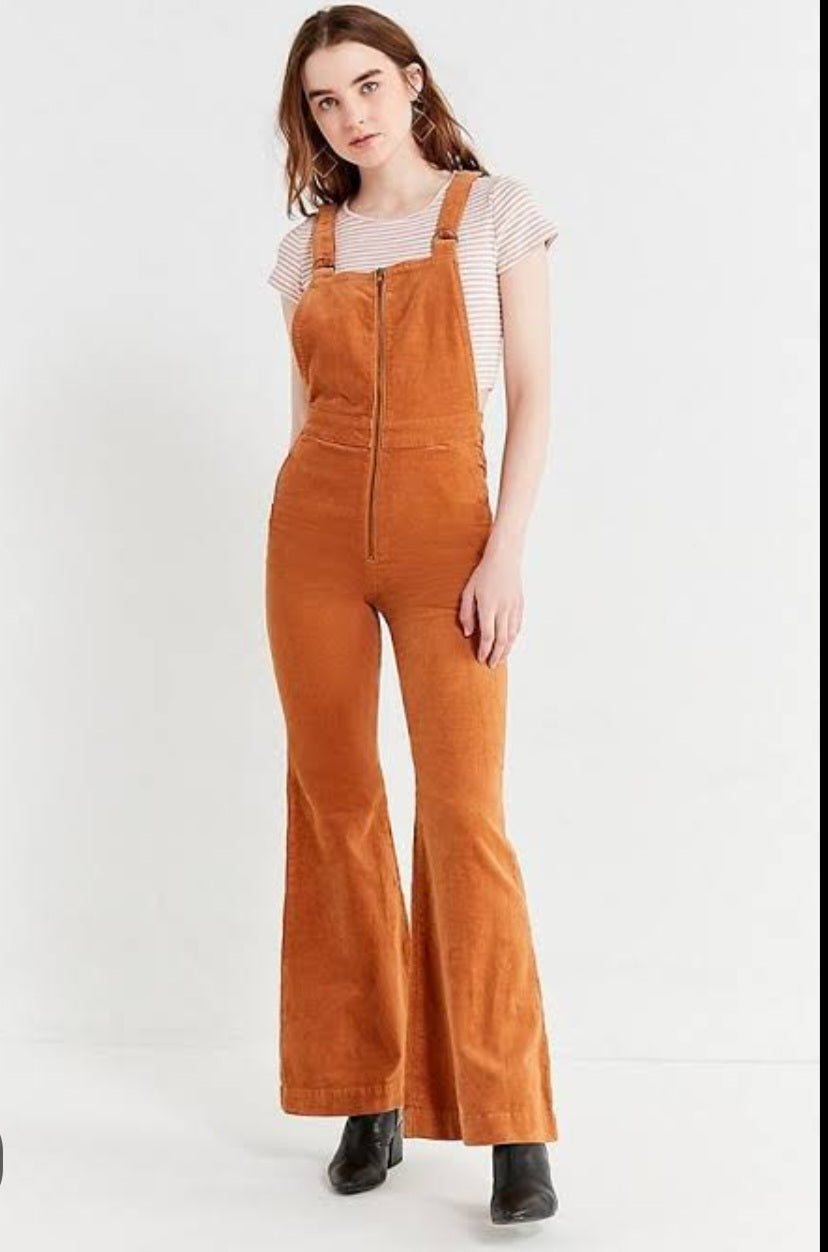 Person wearing brown corduroy overalls on a white background