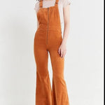 Person wearing brown corduroy overalls on a white background