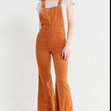 Person wearing brown corduroy overalls on a white background