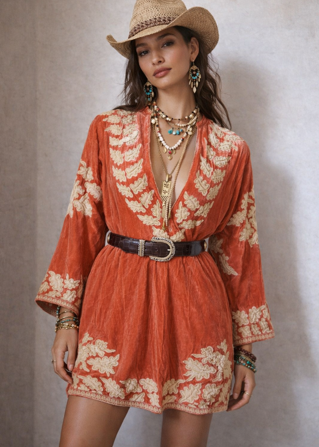 Woman wearing a red floral dress and cowboy hat against a neutral background