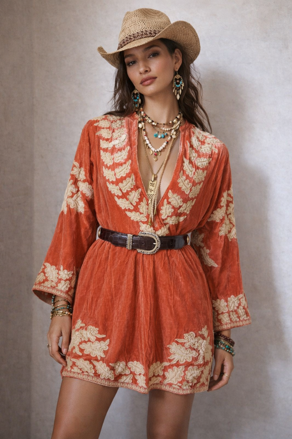 Woman wearing a red floral dress and cowboy hat against a neutral background
