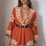 Woman wearing a red floral dress and cowboy hat against a neutral background