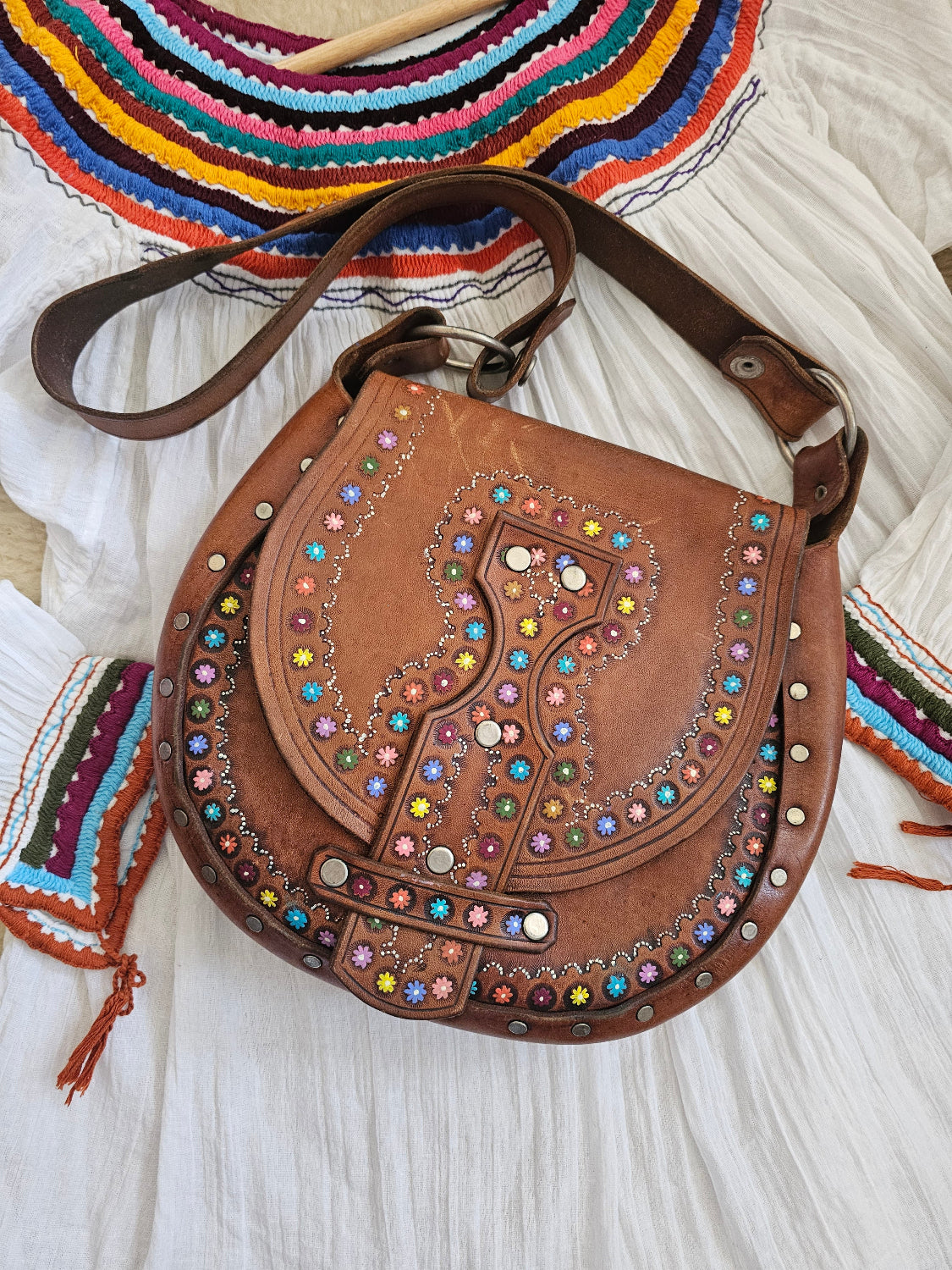 Brown leather bag with colorful gemstones on a textured surface
