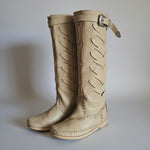 Pair of beige knee-high boots on a light gray background