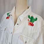 White jacket with embroidered designs on a wooden surface