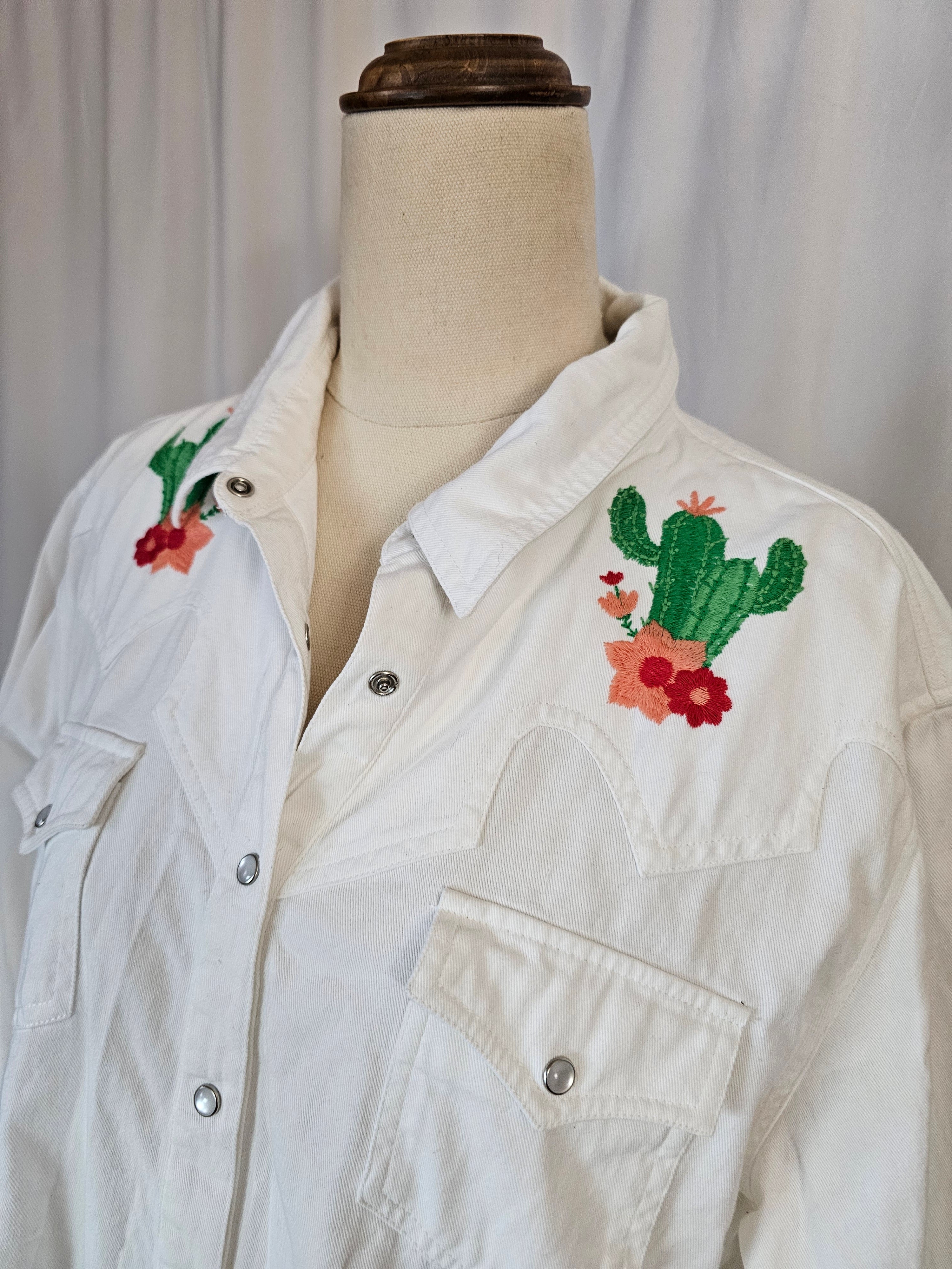 White jacket with embroidered designs on a wooden surface