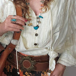 Person wearing a white blouse with floral skirt and accessories
