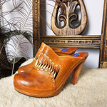 Vintage Wild Pair Tan Leather Mules – Size 37 with carved wood-look heels and fringe detailing, displayed on faux fur with boho decor.