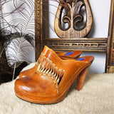 Vintage Wild Pair Tan Leather Mules – Size 37 with carved wood-look heels and fringe detailing, displayed on faux fur with boho decor.