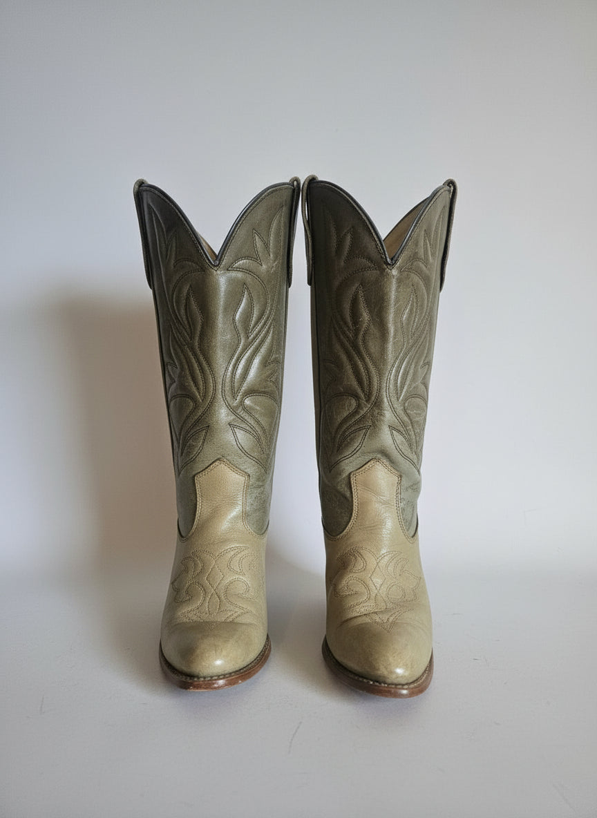 Pair of beige cowboy boots with intricate patterns on a white background
