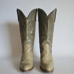 Pair of beige cowboy boots with intricate patterns on a white background