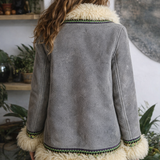 Person wearing a gray jacket with white fur trim in a home setting