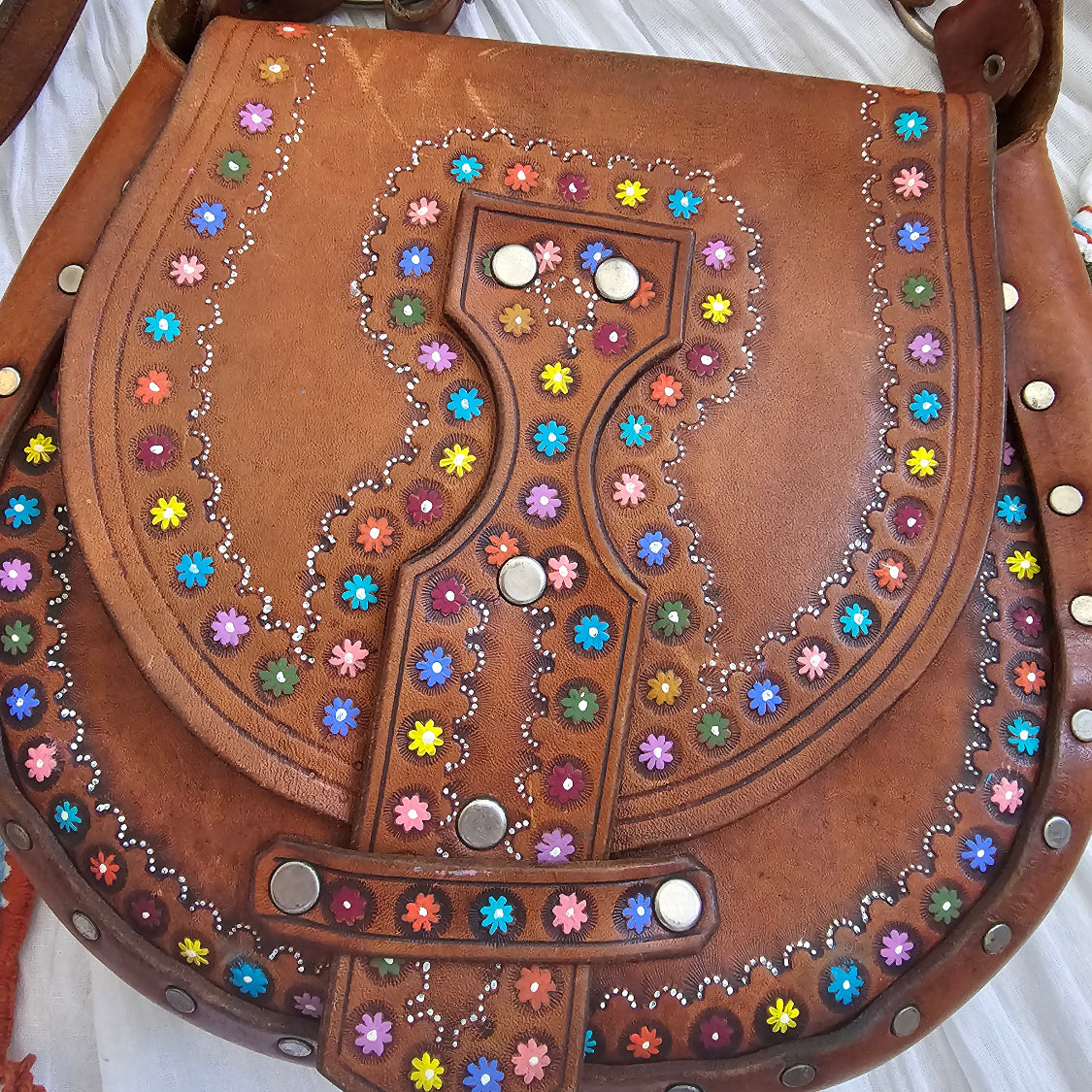Brown leather bag with colorful gemstones on a white background