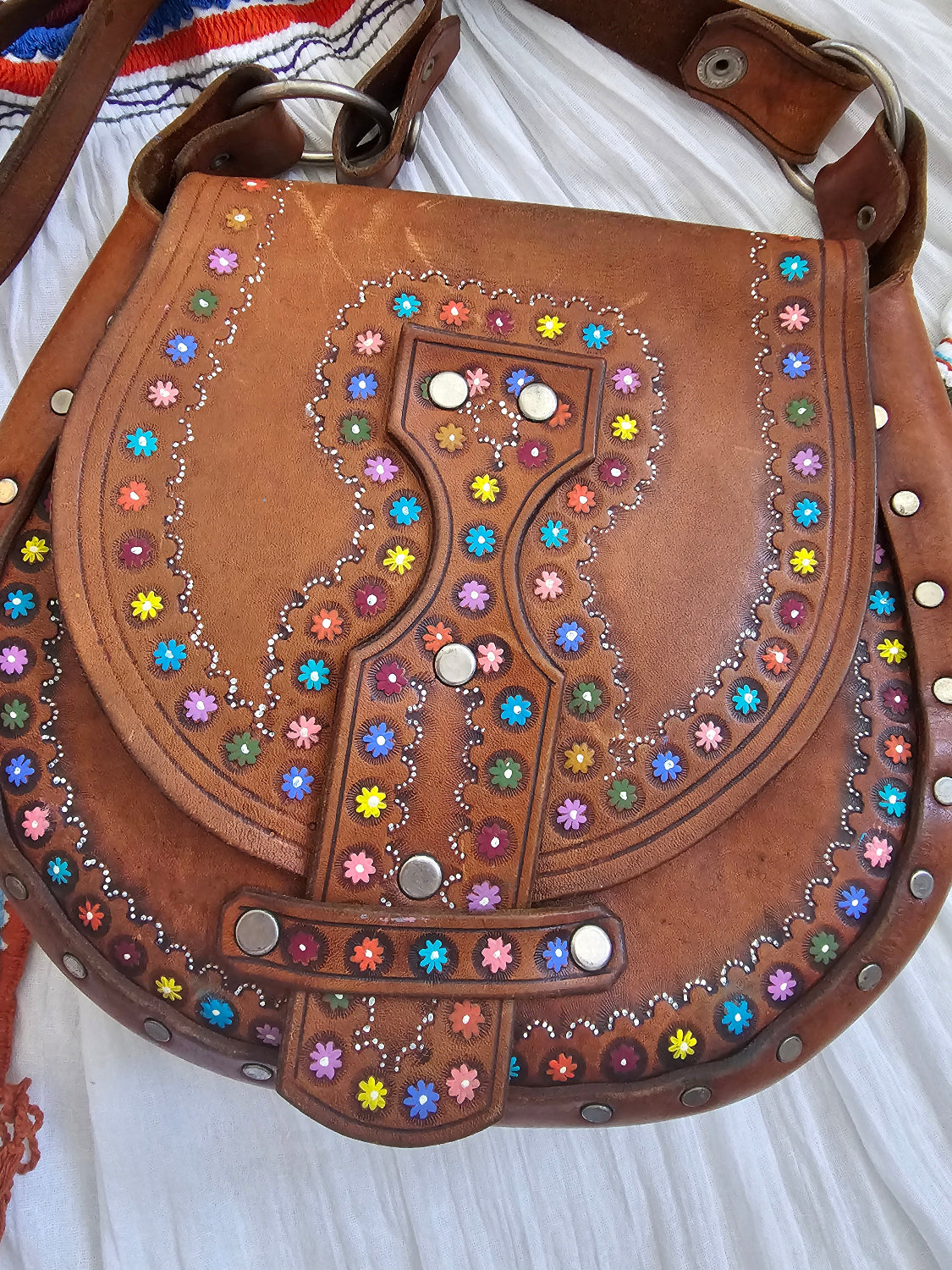 Brown leather bag with colorful gemstones on a white background