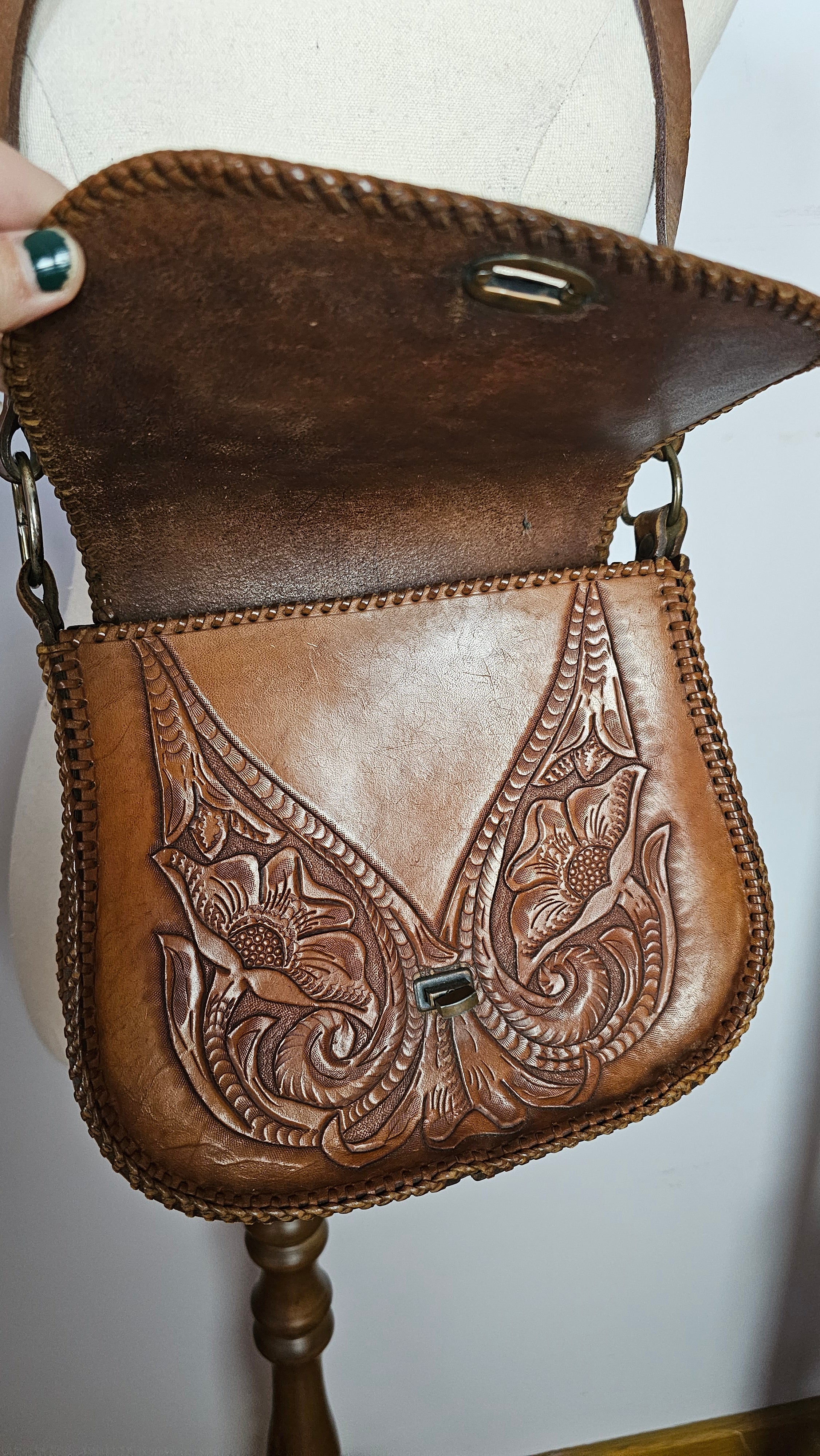 Brown leather bag with intricate embossing on a white background