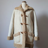 Beige coat with brown fur trim on a mannequin against a neutral background